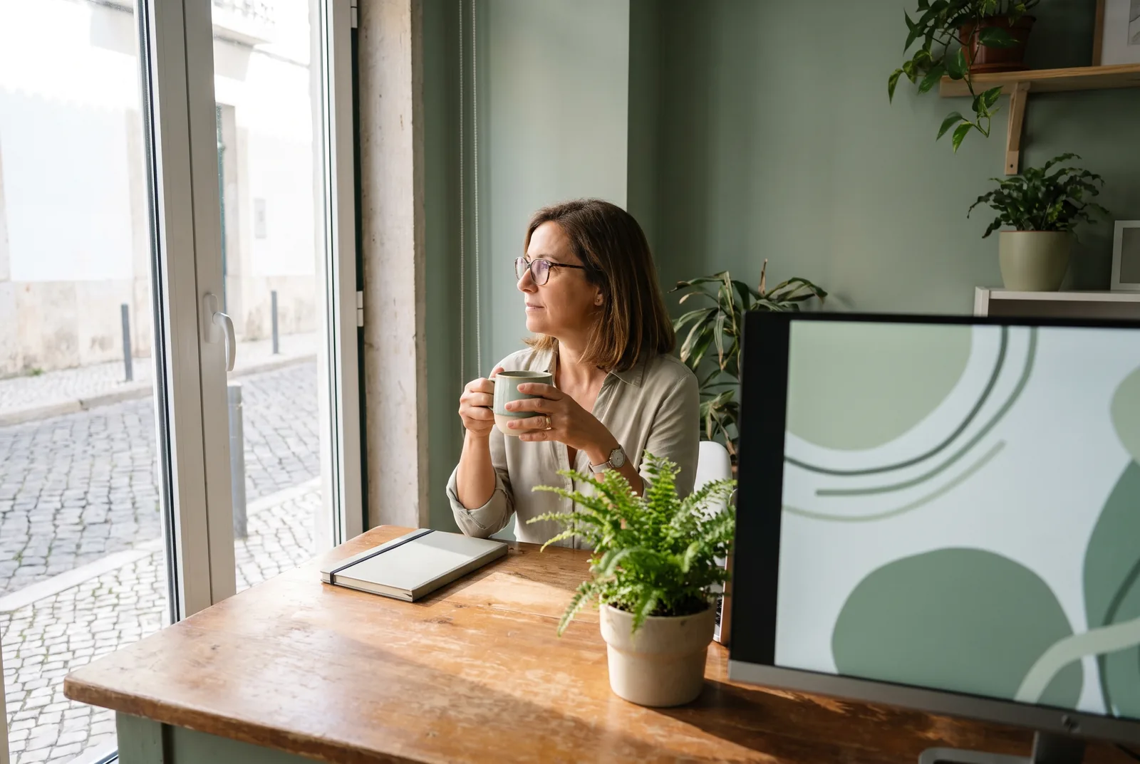 Escritório arrumado e calmo de manhã, com um café junto à janela